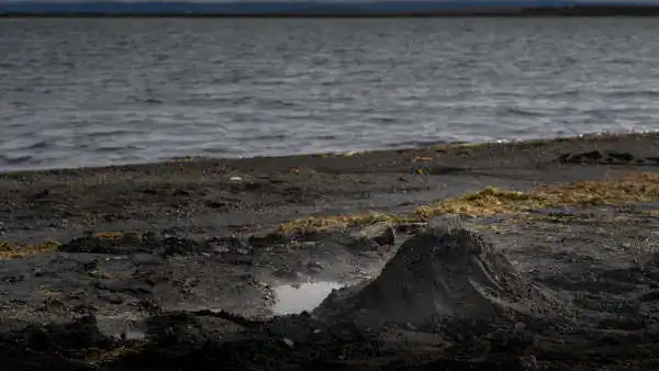 A steaming mound of black sand has a road put on top of it